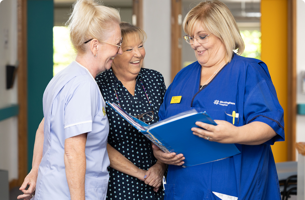 Image is of a nurse holding a binder with two people